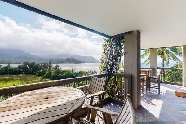 Covered balcony overlooks fields, mountain scenery, and distant ocean waters