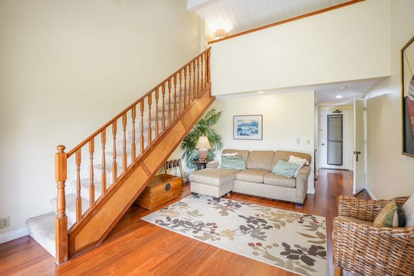 Spacious living area highlights hardwood floors, staircase, and inviting decor