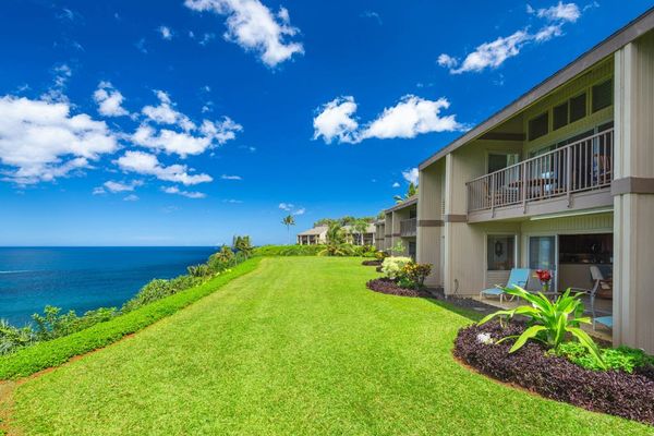 Coastal property exterior features manicured lawns, gardens, and ocean views