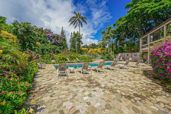 Poolside setting features seating, tropical greenery, and open skies