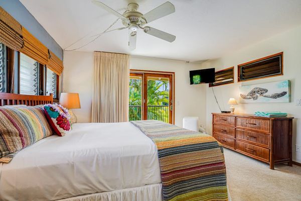 Spacious Bedroom Setup featuring Wooden Dresser, Mounted TV & Ceiling Fan