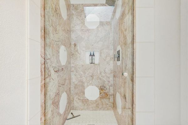 walk-in shower features large-format beige veined porcelain tiles