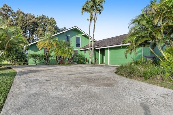 Curving gravel approach welcomes guests beneath palms and leafy shade