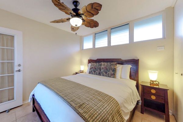 Bedroom, featuring a king bed, French doors, and a palm leaf fan.