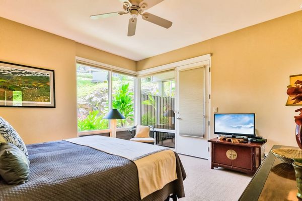 Master bedroom with king bed, flat screen tv and large windows for tropical views and private lanai access.