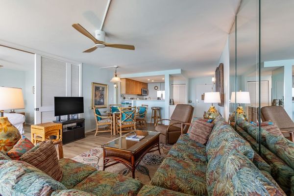 Living room with sofa bed, flat screen tv and rays of natural light streaming in from the lanai.