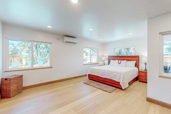 First Bedroom features crisp linens warm wood floors and garden light