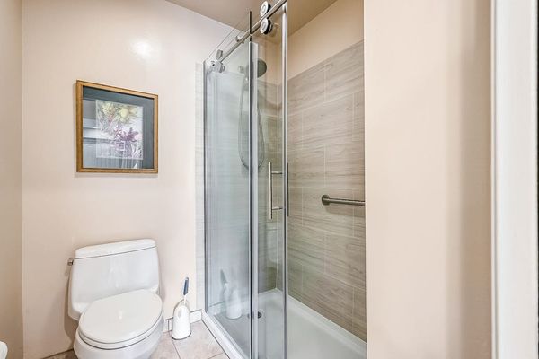 Full bathroom features glass shower enclosure toilet and wall art