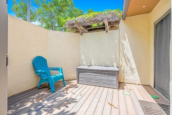Sunny patio features comfortable chairs deck seating and garden walls