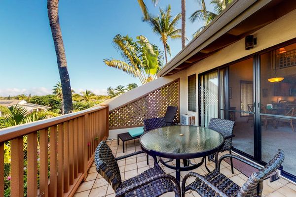 Balcony dining set overlooks palm trees and Maui resort landscaping