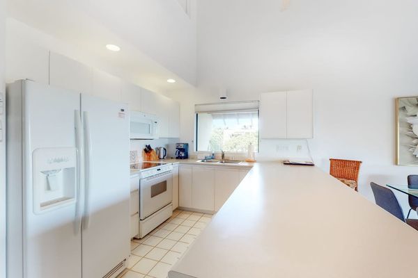 Bright kitchen offers generous counters, white cabinetry, and island seating