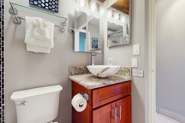 Spotless bathroom presents a vessel sink, mirror, and storage cabinet