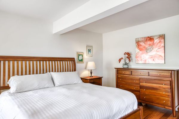 Well-Appointed Bedroom with King Bed, Matching Wooden Dresser, and Floral Wall Art