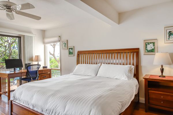 Cozy Bedroom Setup featuring Hardwood Bed Frame, Work Desk, and Tropical Views