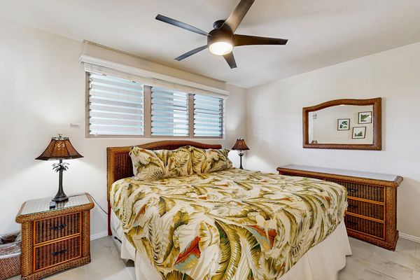 First bedroom features king bed botanical quilt nightstands and fan