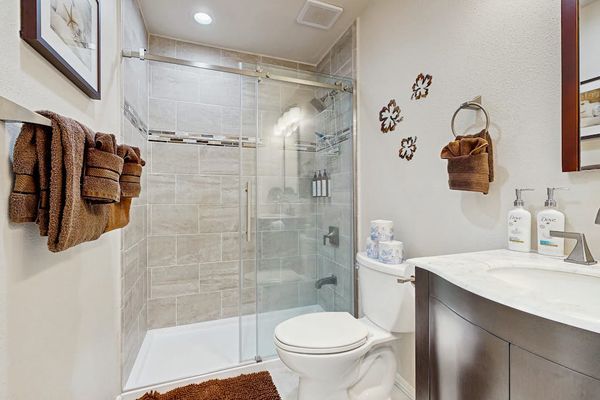 Full bathroom includes glass shower toilet vanity and fresh towels