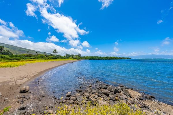 Rocky shoreline frames calm Pacific waters beneath bright island skies