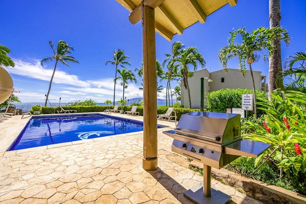 Barbecue area offers grill, ocean views, palms, and shaded shelter