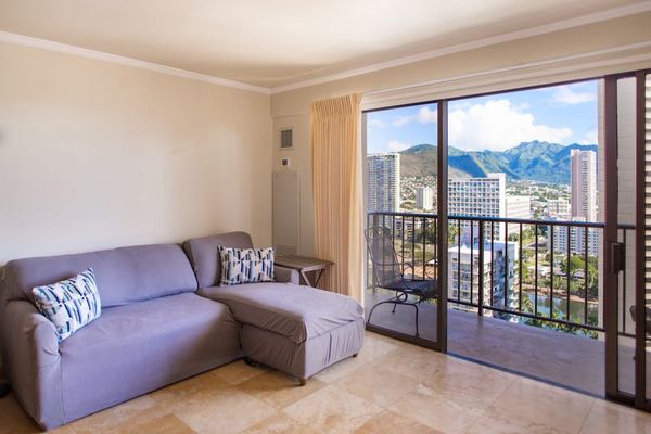 Cozy living area with a sleeper sofa and direct access to the private balcony overlooking Waikiki.