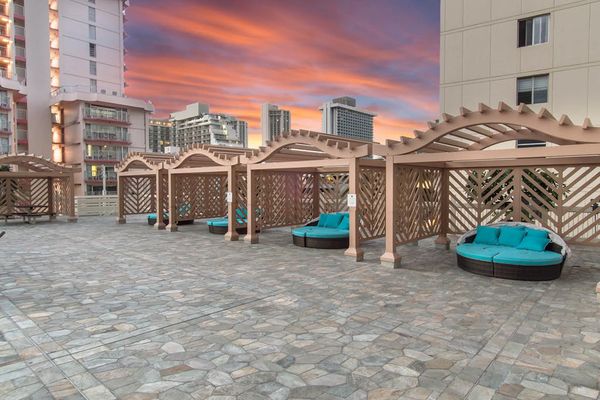 The sprawling pool deck offers multiple designated lounging areas with beautifully designed wooden pergolas, providing plenty of shaded seating to enjoy the spectacular city skyline.
