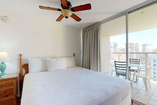 The primary bedroom offers direct sliding-door access to the balcony, a cooling ceiling fan, and lovely elevated city views.