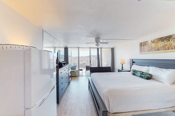 Bright studio floor plan with light flooring, a king bed setup, and floor-to-ceiling glass sliding doors opening to the balcony.