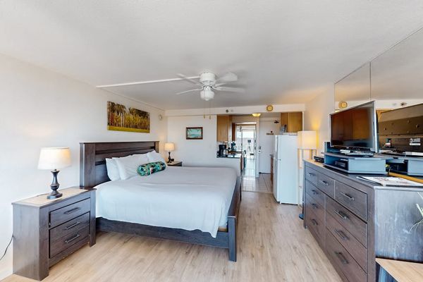 This open-concept studio offers a plush bed, ceiling fan, and flat-screen TV in a bright and inviting layout.
