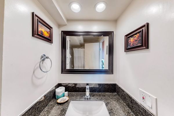 The bathroom vanity features a dark granite countertop, an undermount sink, a large framed mirror, and complimentary amenities.