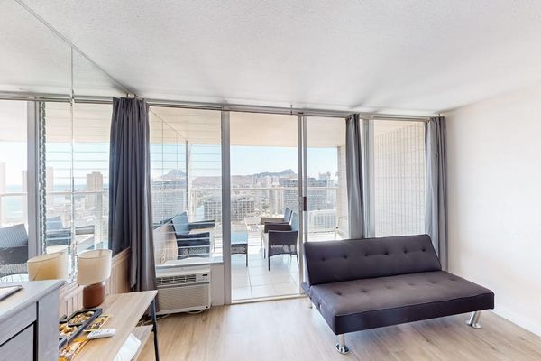 Convertible futon sofa positioned adjacent to floor-to-ceiling sliding glass doors, seamlessly blending indoor living with the private balcony.