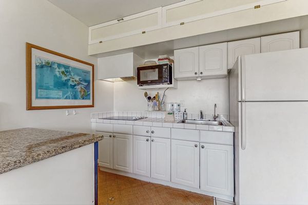 Kitchen workspace includes counters, appliances, cabinetry, and colorful artwork nearby