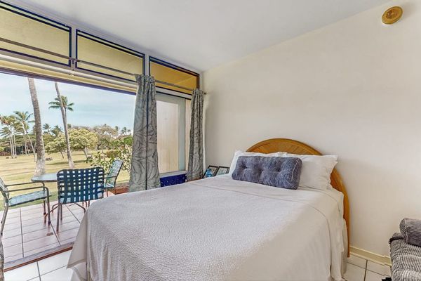 Studio bed faces glass doors with ocean views and lamp
