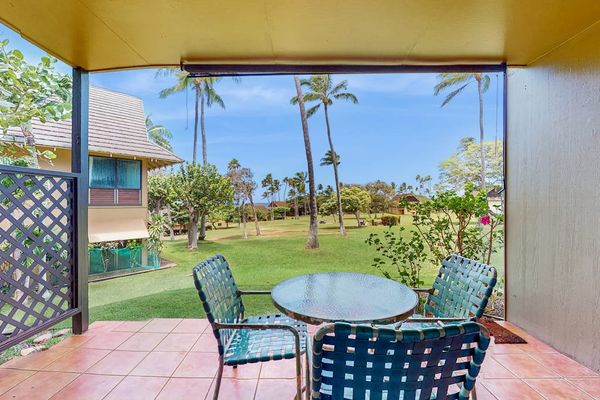 Covered patio dining area overlooks resort gardens, palms, and ocean