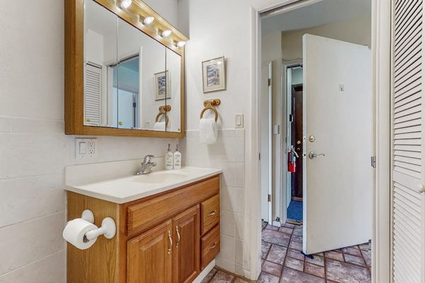 Bathroom vanity area includes mirror, sink, toiletries, towels, and doorway