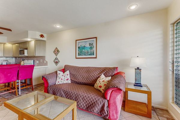 Living room includes patterned sofa, accent chairs, counter, and artwork