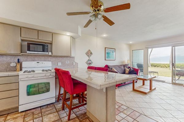 Open kitchen features island seating, appliances, cabinetry, and ocean-facing windows