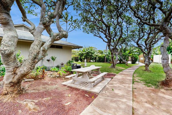 Garden walkway winds past tropical plants, stone paths, and outdoor seating
