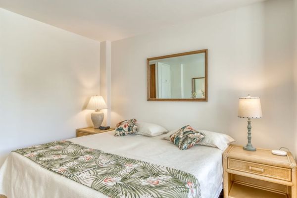 King Bed Setup Flanked by Matching Nightstands and Decorative Wall Mirror