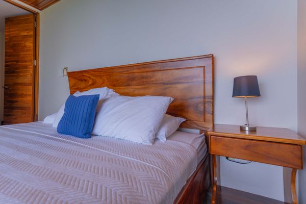A comfortable bedroom setup with soft linens, bedside lighting, and elegant wood accents.