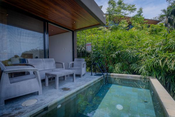 Covered poolside sitting area with peaceful greenery all around.