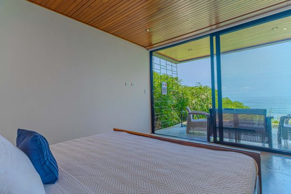 Bedroom with large sliding doors opening to lush greenery and natural light.