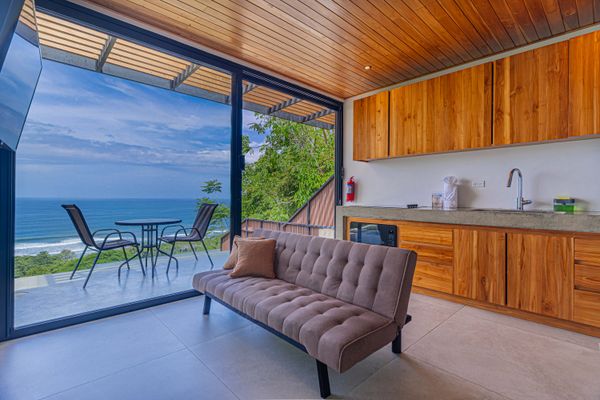 A bright and inviting living space with kitchenette, comfortable seating, and ocean views.