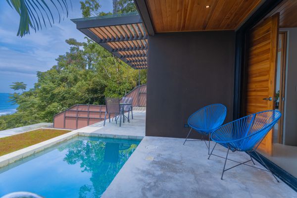 Covered poolside terrace with lounge seating and beautiful coastal views.