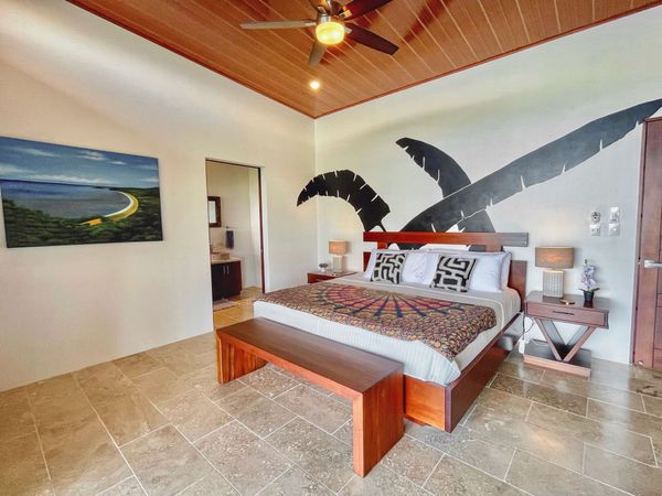 Suite #1 with king-size bed, ocean views, patio access, A/C, ceiling fan and en-suite bathroom.