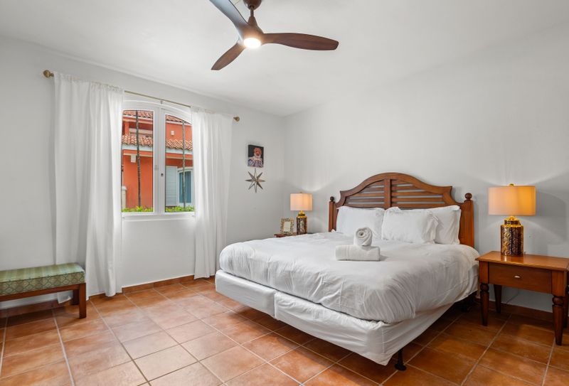 bedroom with airconditioner, ceiling fan, king sized bed, bed lamps, balcony, wall art