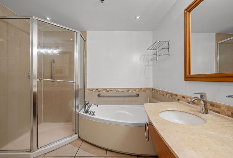 Unwind in the beautifully designed bathroom, featuring a refreshing glass-enclosed shower and a separate, inviting bathtub, perfect for a soothing soak.