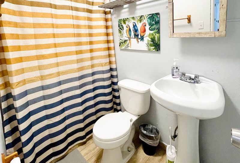 Refresh and rejuvenate! Our clean and modern bathroom features a spacious shower with a fun, striped curtain, ensuring a bright start to your day.
