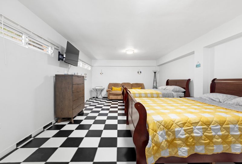Stylish double bedroom includes a flat-screen TV, soft sofa and wooden cabinet.
