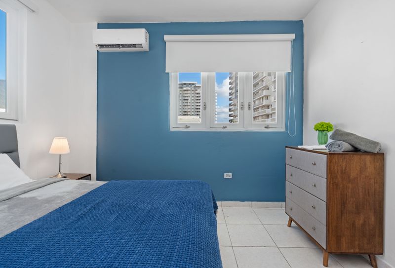 A spacious main bedroom with a comfortable bed and calming blue accent wall.