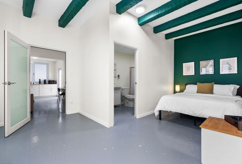 Stylish and snug bedroom accented with a chic emerald wall – ideal for a peaceful city stay. Includes a cozy bed, modern features, and a private bathroom for ease.
