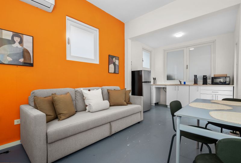 Modern living room featuring a stylish couch, coffee table, chairs, and a mounted flat-screen TV.